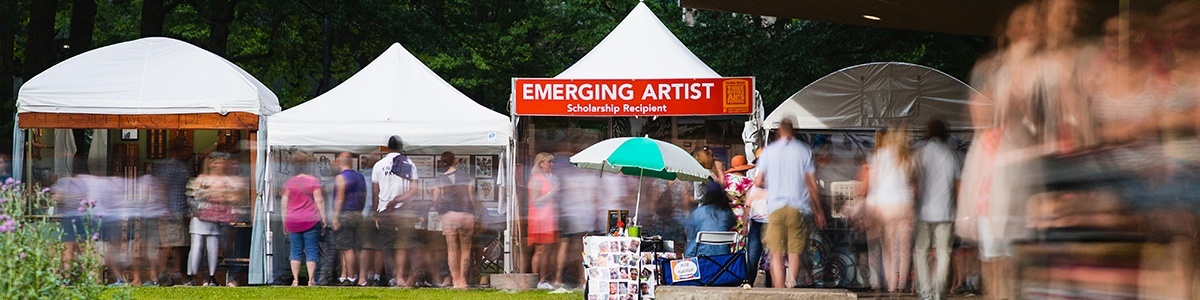 a photo of crowds walking past an 'emerging artist' booth