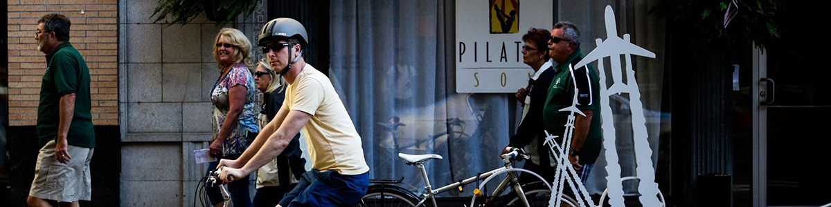 people biking and walking on a street in downtown pittsburgh