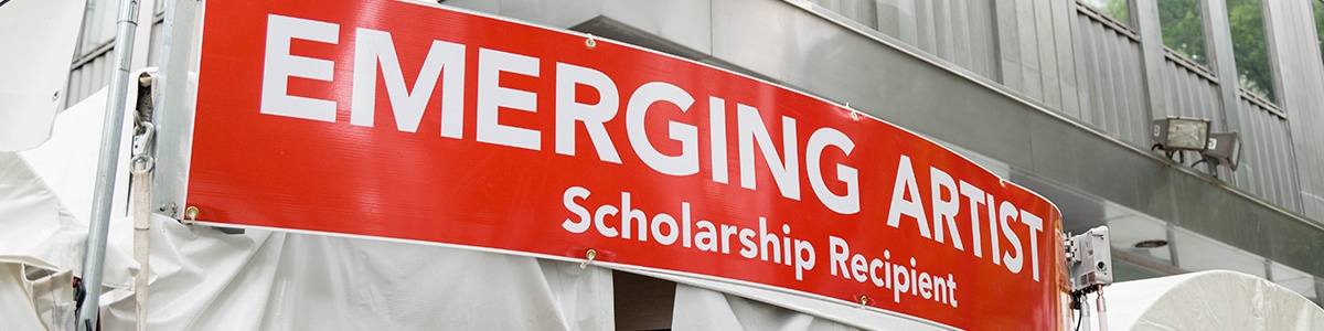 a banner that says 'emerging artist' sits above an artist display booth