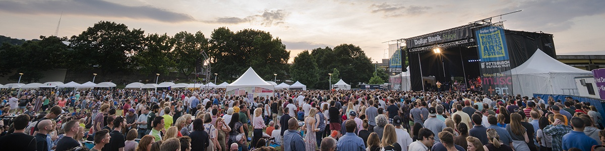 a large crowd fills point state park during an evening concert