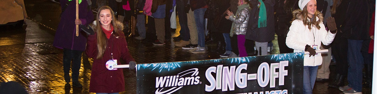two williams sing off finalists walk in a past highmark first night pittsburgh parade with a banner