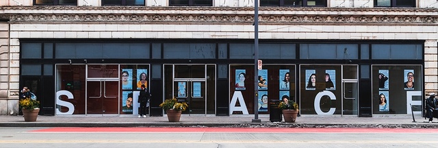 posters with collective members headshots on the side of space gallery